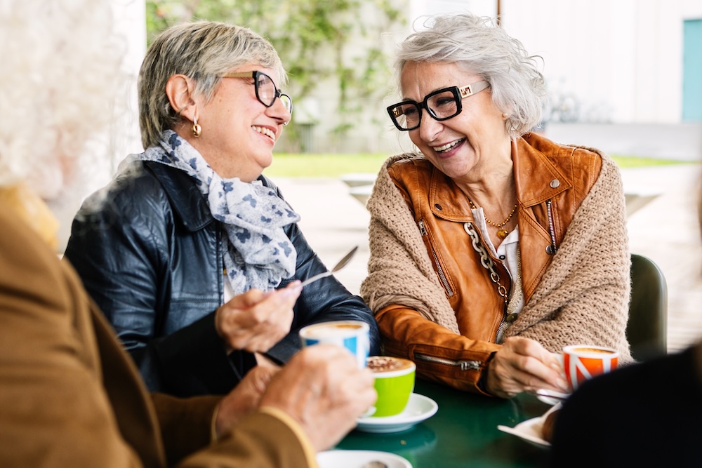 Senior women outside enjoying a coffee at a cafe and talking about senior apartments melvindale mi